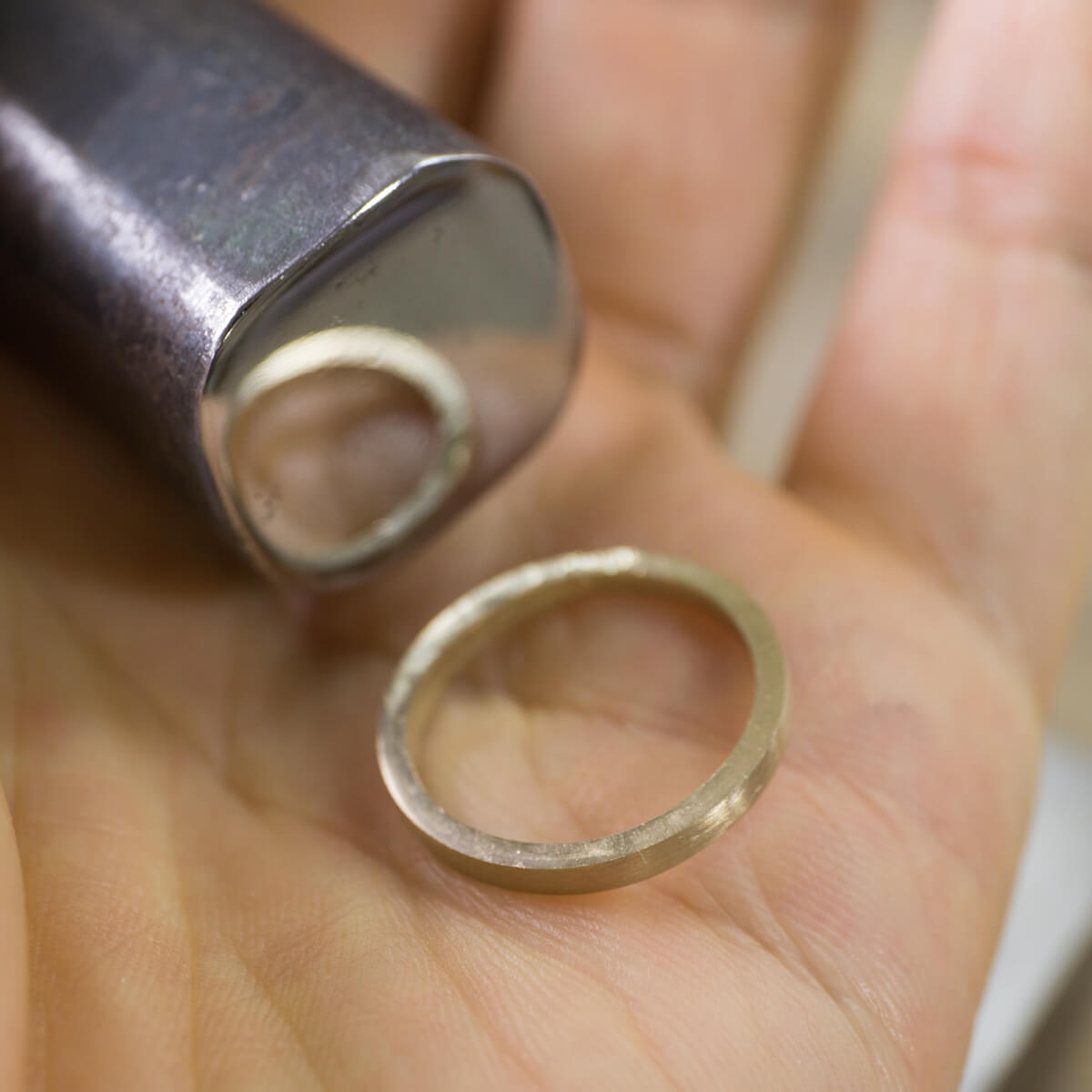 オーダーメイドマリッジリングの制作風景　ジュエリーのアトリエ　ゴールドリング、金槌を手に　屋久島でつくる結婚指輪