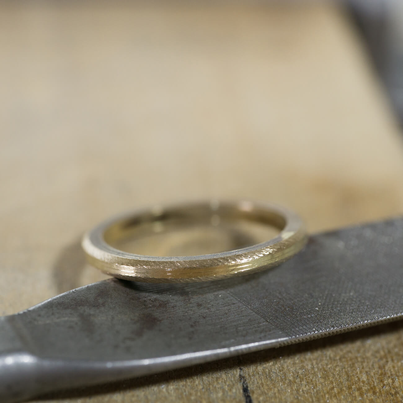オーダーメイドマリッジリングの制作風景　ジュエリーのアトリエ　作業場に指輪、ヤスリの上　ゴールド　屋久島で作る結婚指輪